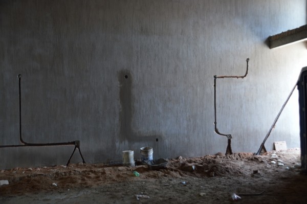 Oddly, tracks are cut into the freshly plastered wall for the conduit. When that's in, new plaster goes over it.